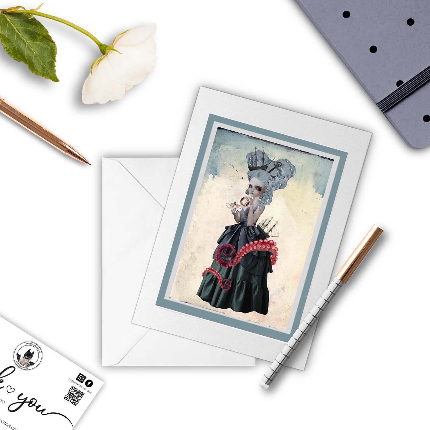 Amphitrite Art greeting card with a pen and other stationary arranged around it.