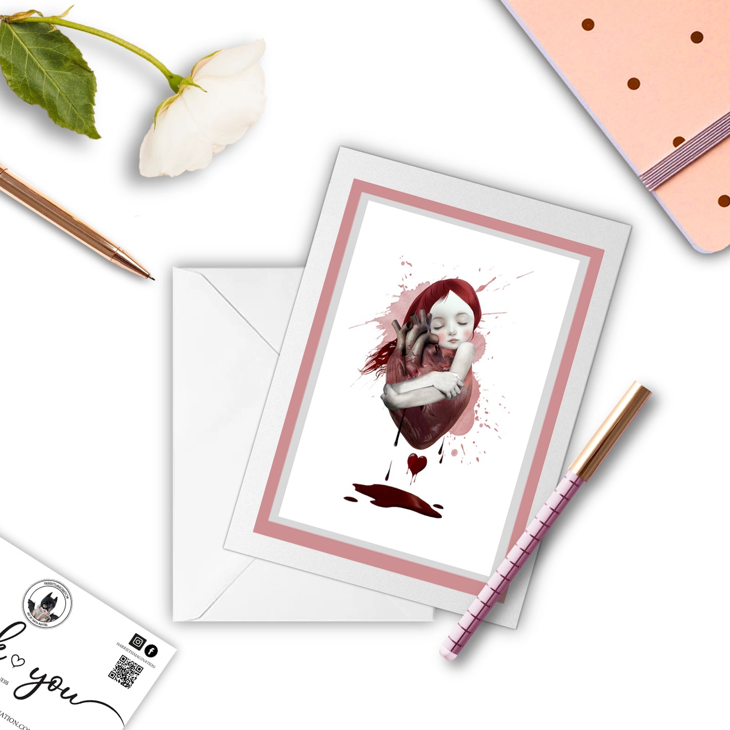 Anatomical heart greeting card, with a pen and other stationaryitems arranged around it.