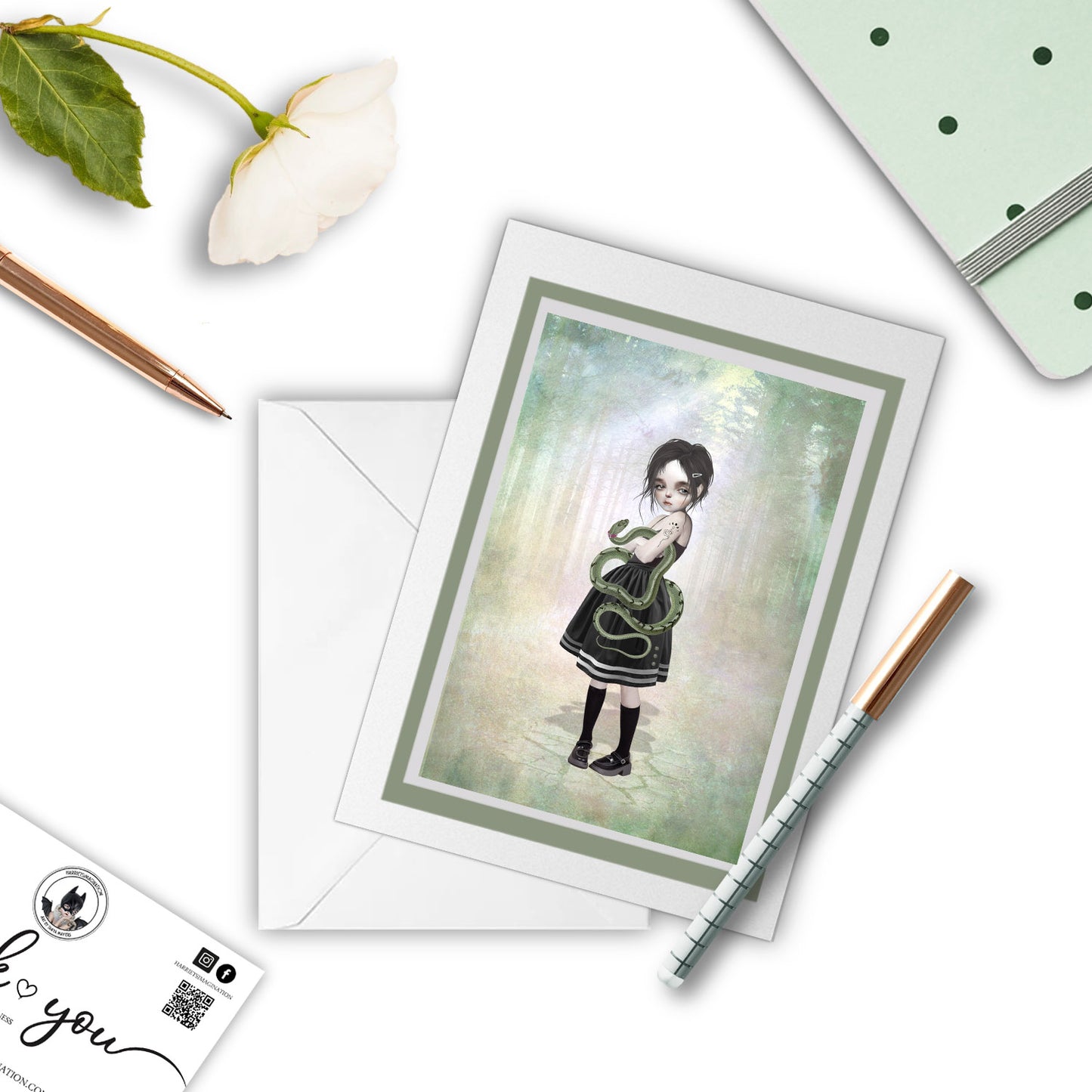 Girl and pet snake greeting card beside a notebook and pen – perfect for gifting or writing a quirky, poetic note.