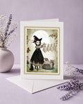 Blank frameable art greeting card featuring a gothic witch girl hanging sheet ghosts on a clothesline next to a white envelope