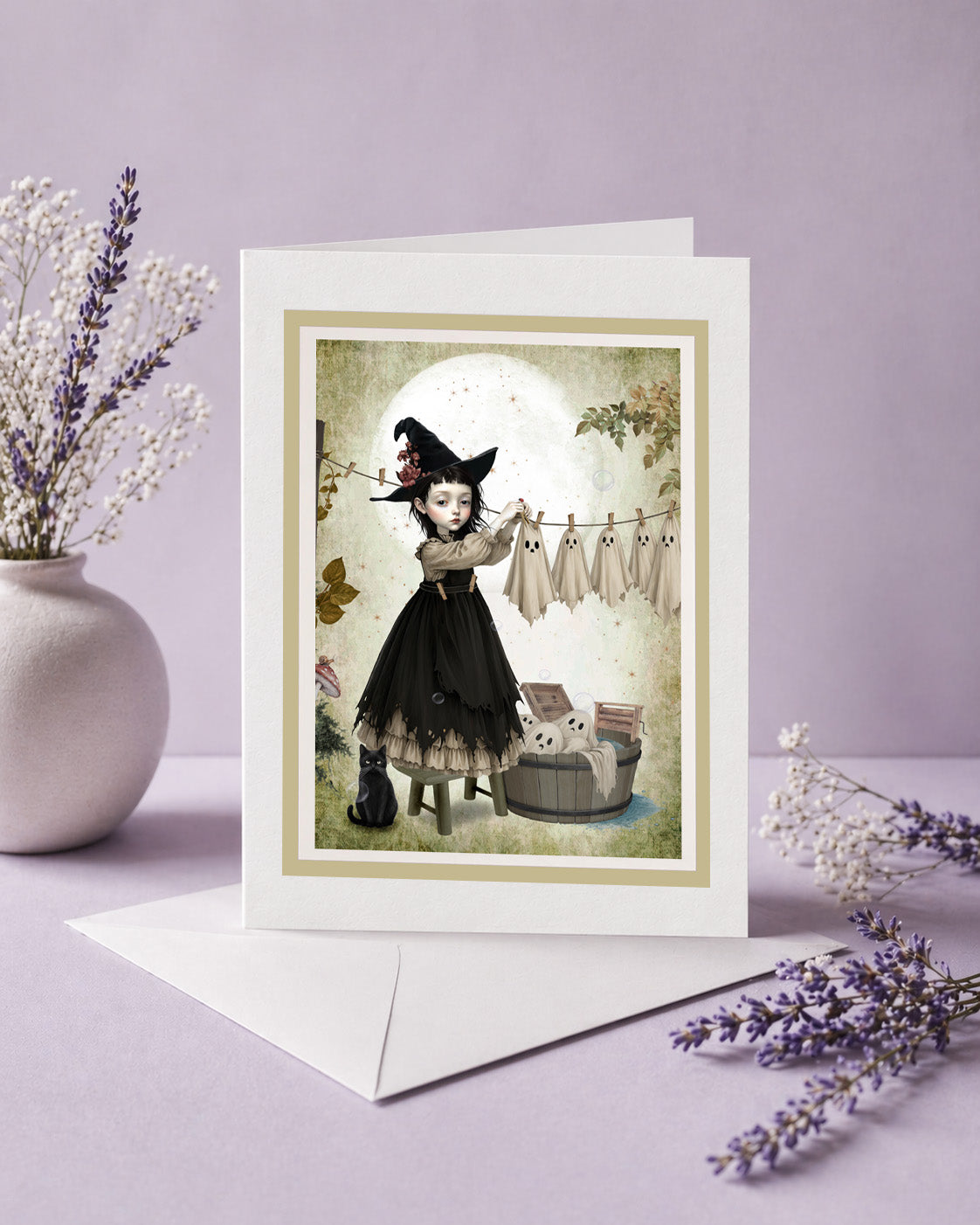 Blank frameable art greeting card featuring a gothic witch girl hanging sheet ghosts on a clothesline next to a white envelope