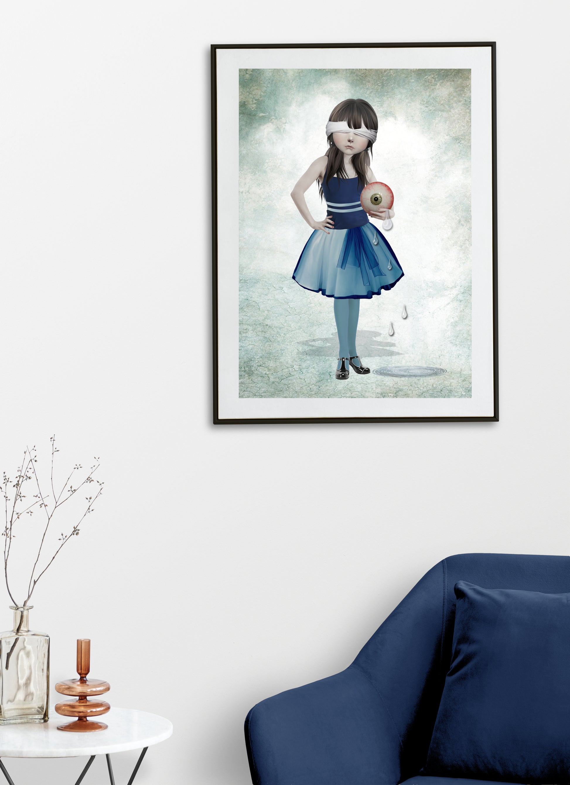 Blindfolded girl and an oversized eyeball art print hanging on the wall of a modern living room. Perfect for adding a weird edgy touch to home decor.