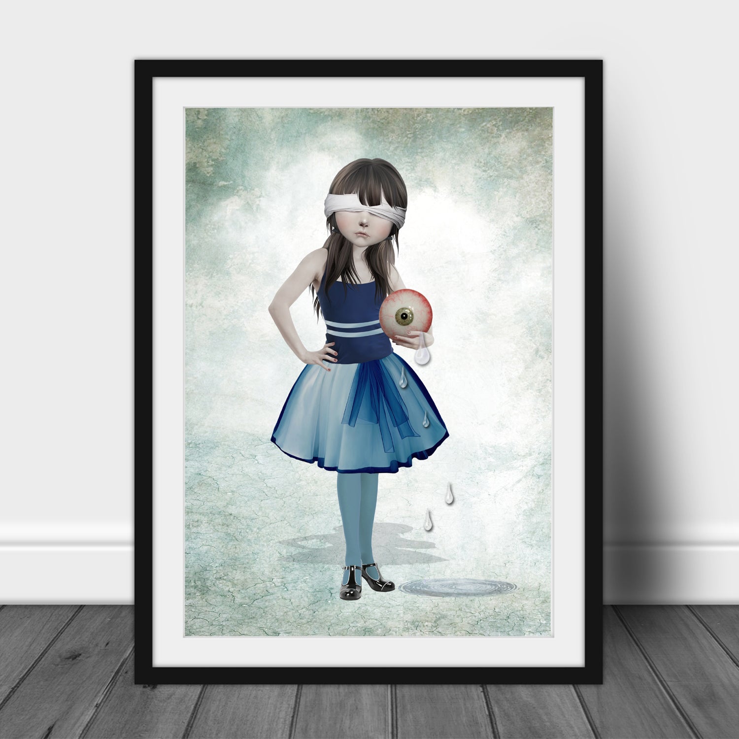 Blindfolded girl and eyeball art print in a sleek frame, set against a white background.
