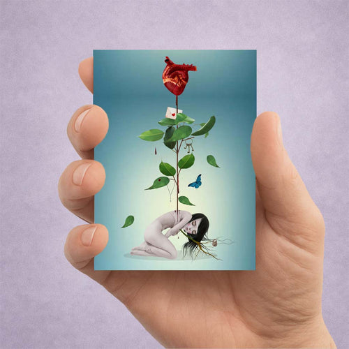 Hand holding an ACEO card with a surreal design of an anatomical heart growing with a plant from a sad girls spine.