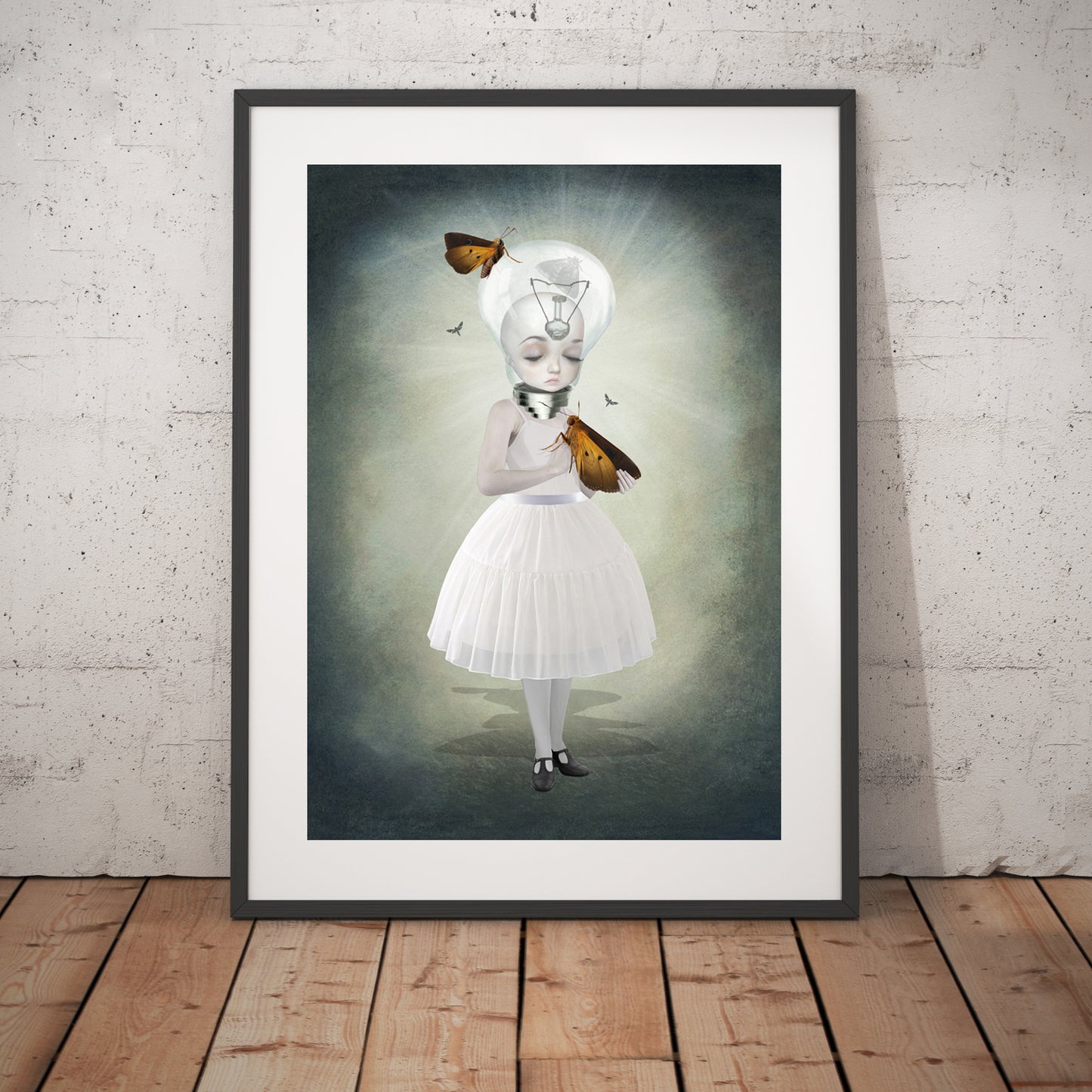 Bulb girl and moths art print in a black frame, standing against a white wall.