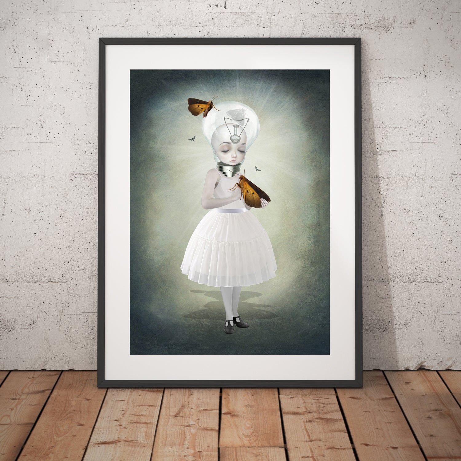 Bulb girl and moths art print in a black frame, standing against a white wall.