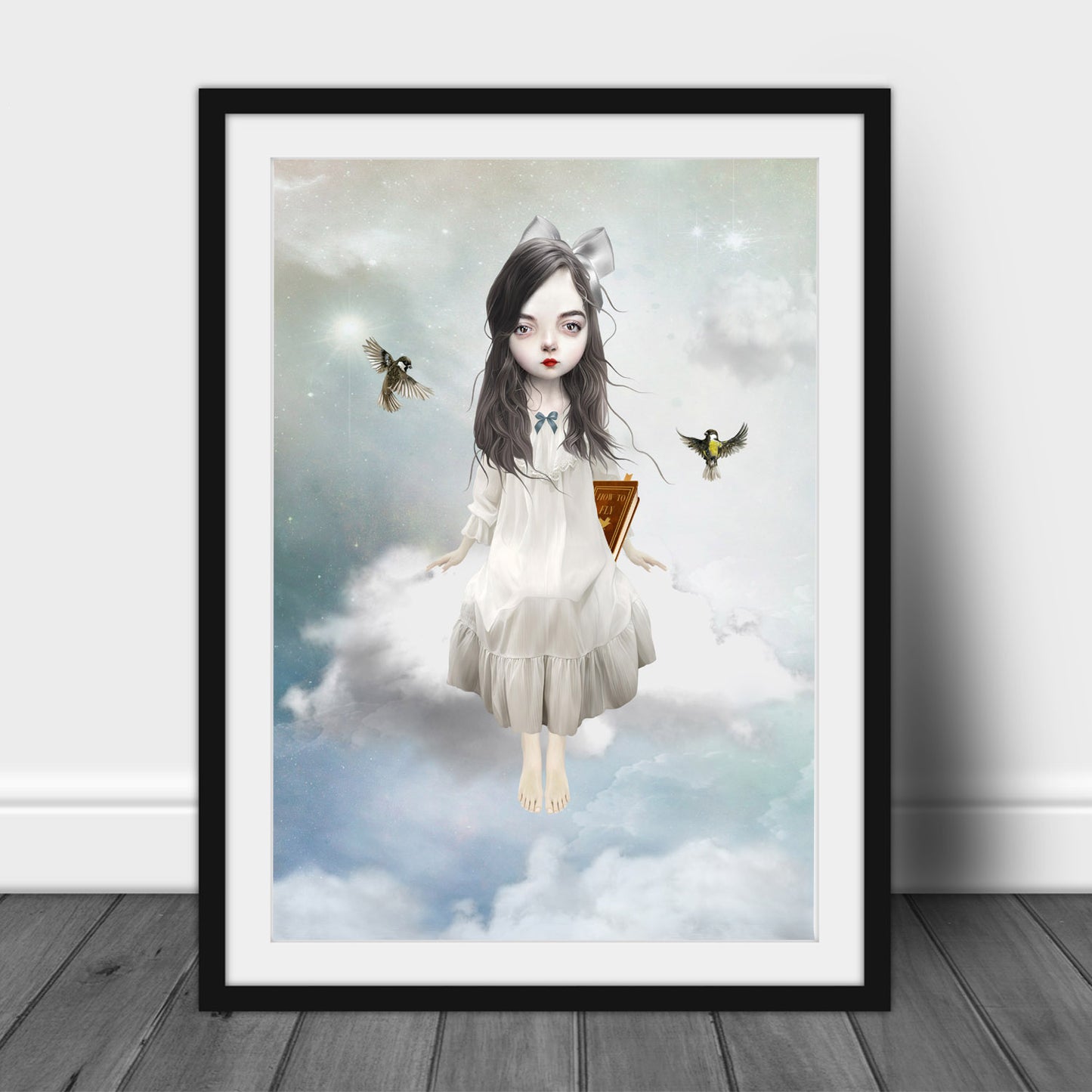 Art print of a girl sitting on a cloud, in a frame, leaned against a wall.
