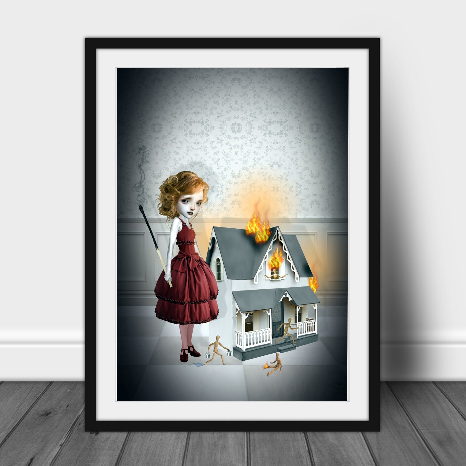Black framed creepy cute art print features a girl standing beside a burning dollhouse, holding an oversized burnt match. As wooden dolls scatter in panic.