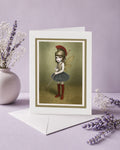 Surreal art greeting card. Featuring a fierce, big-eyed dark fairy dressed as an ancient warrior—complete with a plumed Roman helmet and a sewing needle spear.