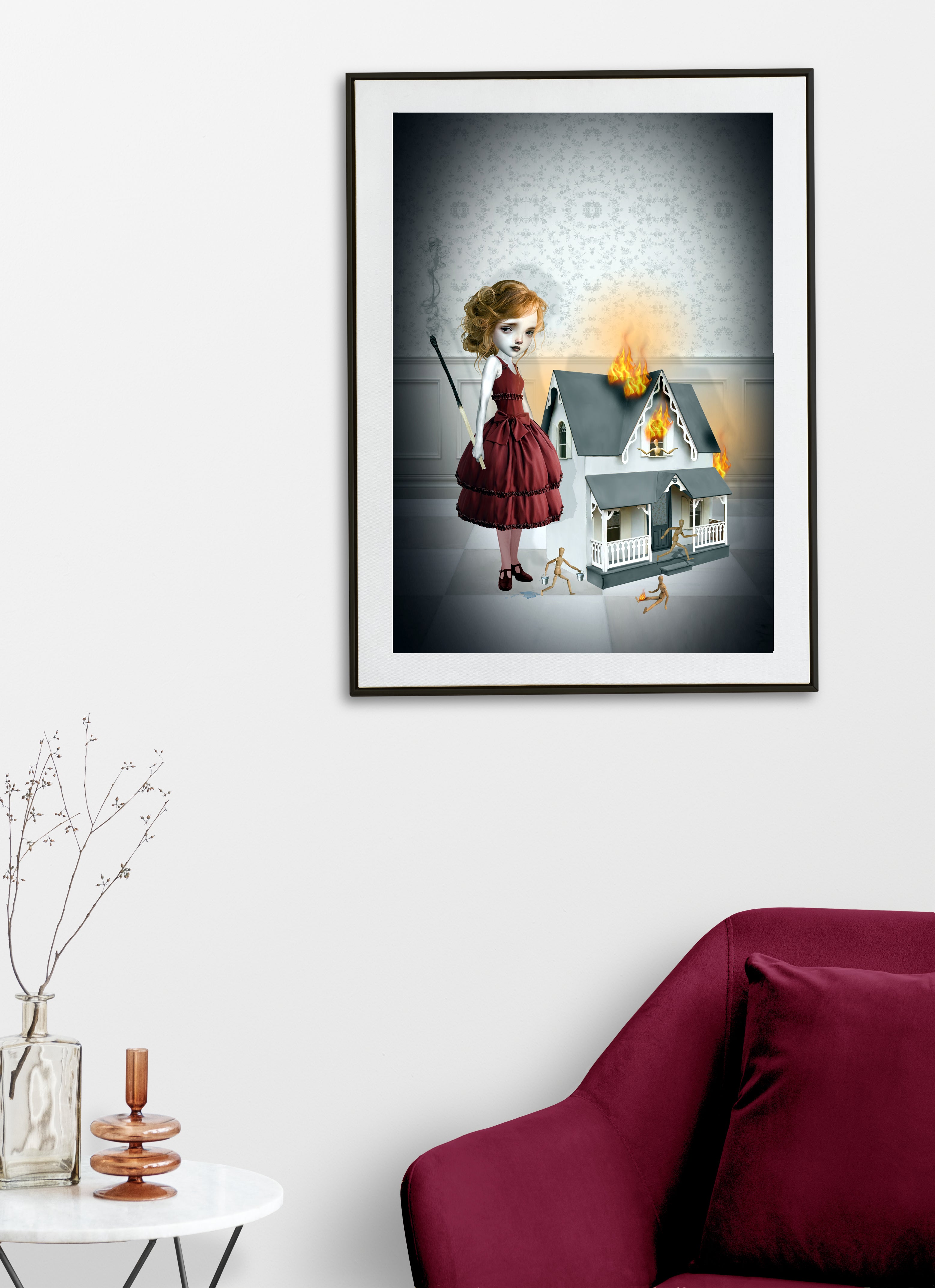 Surreal art print on a living room wall featuring a girl in a red dress holding an oversized burnt match next to a flaming miniature dollhouse, this pop surrealism art piece is filled with eerie details like tiny wooden mannequins fleeing the fire.