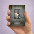 Creepy cute miniature print of a gothic girl watering graves, shown held in a hand.