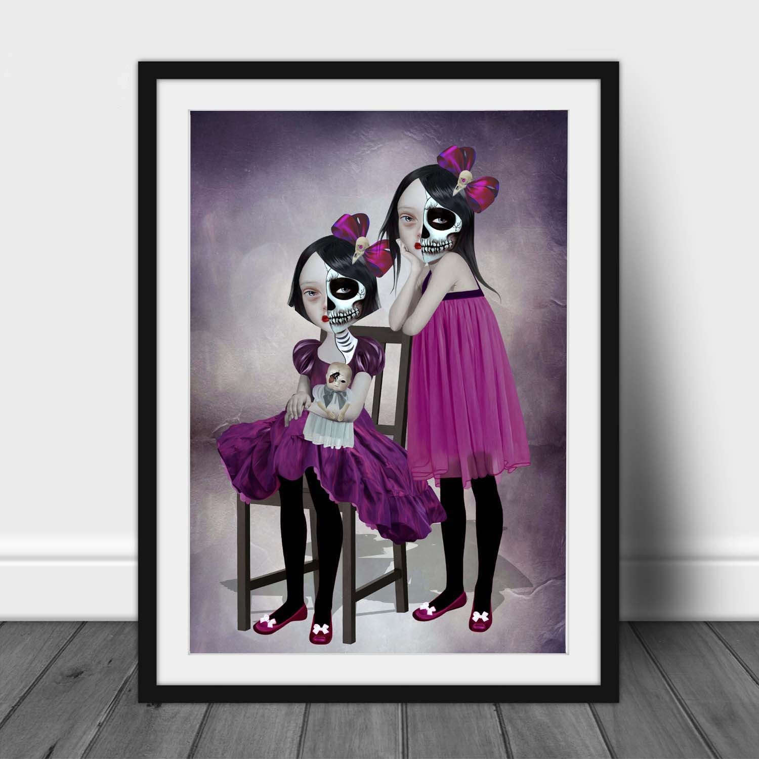 Art print of a day of the dead sisters, in a frame, leaned against a wall.