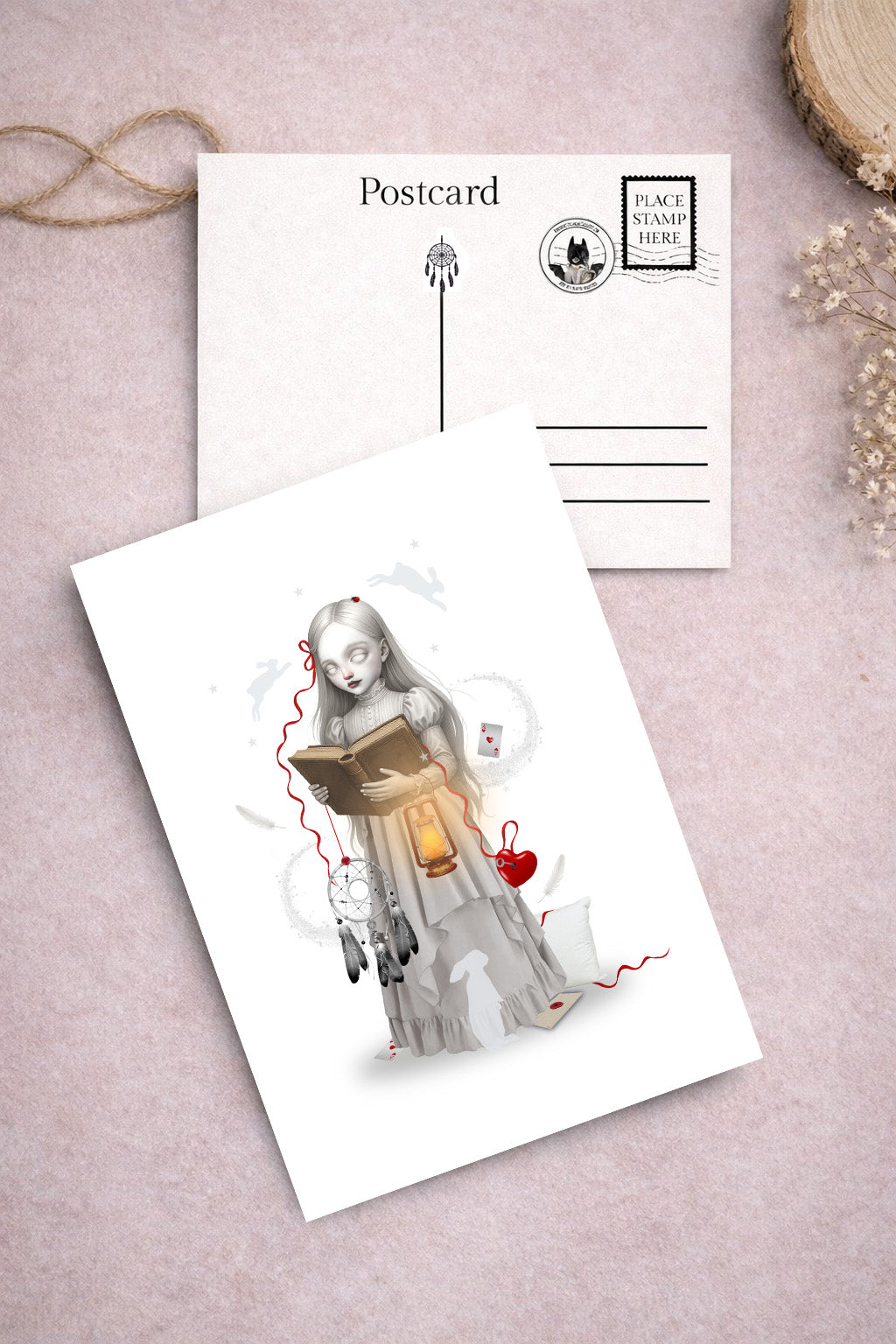 Dreamy art postcard on a light pink surface, one with an illustration of a girl reading a book interpreting dreams.