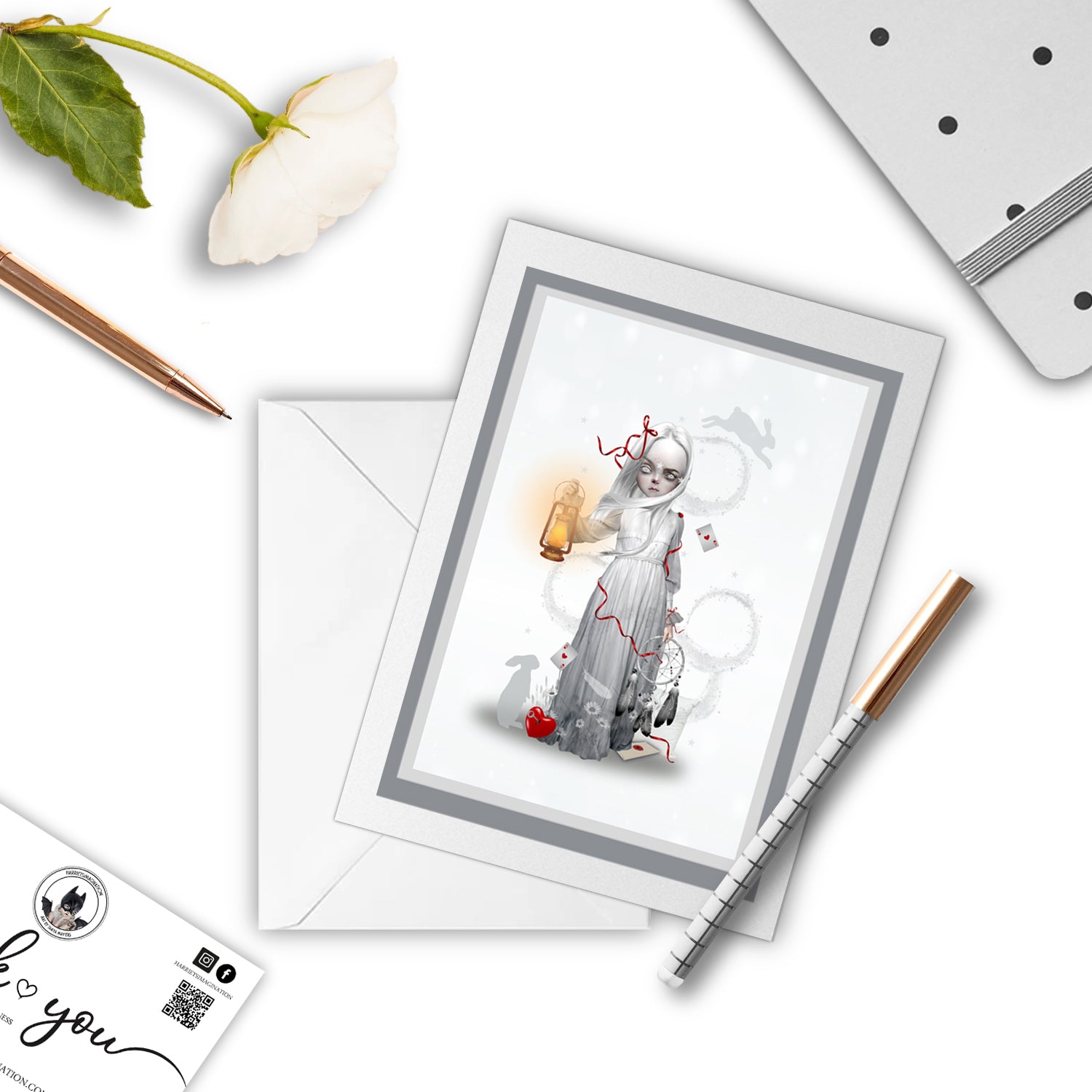 Dreaming Girl Art Greeting Card , with a pen and other stationary items arranged around it.
