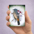 Hand holding a dark fantasy ACEO art card featuring a whimsical fairy comforting a wounded songbird