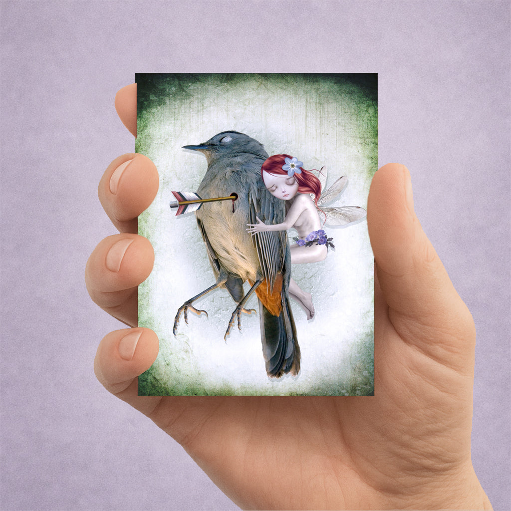 Hand holding a dark fantasy ACEO art card featuring a whimsical fairy comforting a wounded songbird