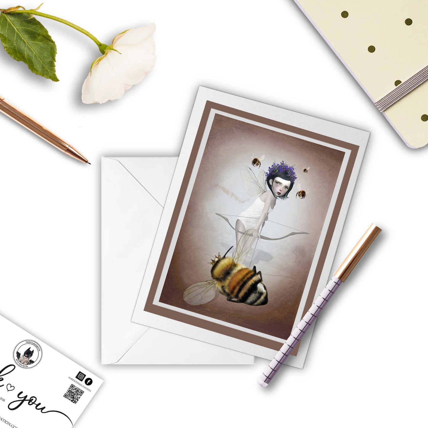 Fairy and queen bee greeting card beside a notebook and pen – perfect for gifting or writing a dark, poetic note.