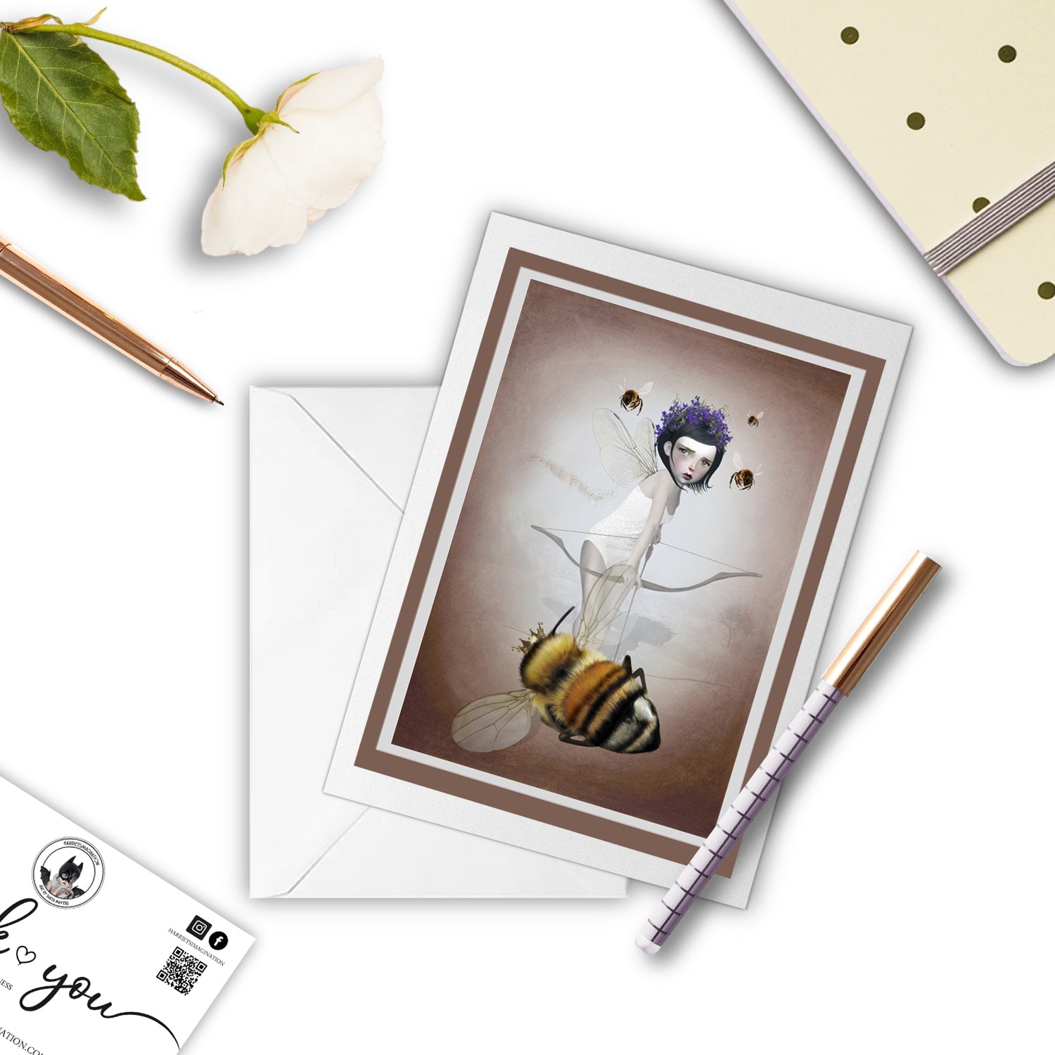 Fairy and queen bee greeting card beside a notebook and pen – perfect for gifting or writing a dark, poetic note.