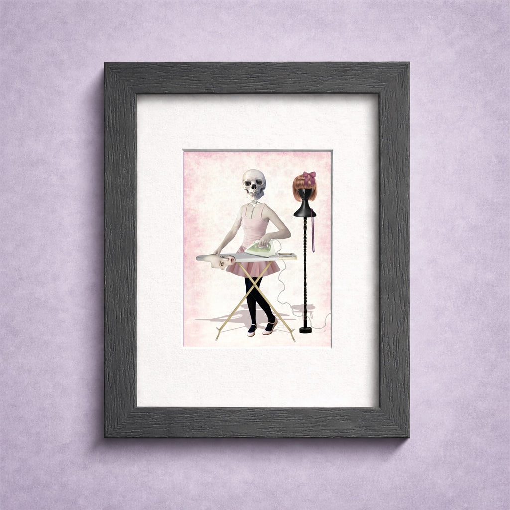Framed artwork of a skeleton ironing her skin suit on a pink background.