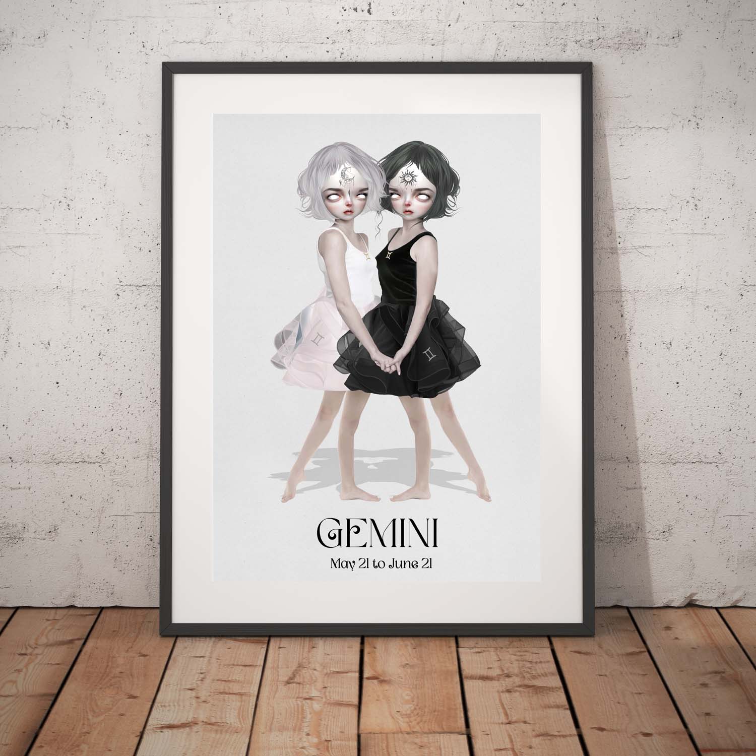 Gemini Twins art print in a black frame, standing against a white wall.