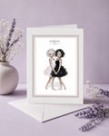 Gemini zodiac birthday card featuring an illustration of twin maidens holding hands—one with white hair in a light dress and one with black hair in a dark dress.