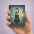 A spooky cute ACEO art card Features a girl catching ghosts—perfect for miniature whimsical gothic decor. Held in hand to display size.