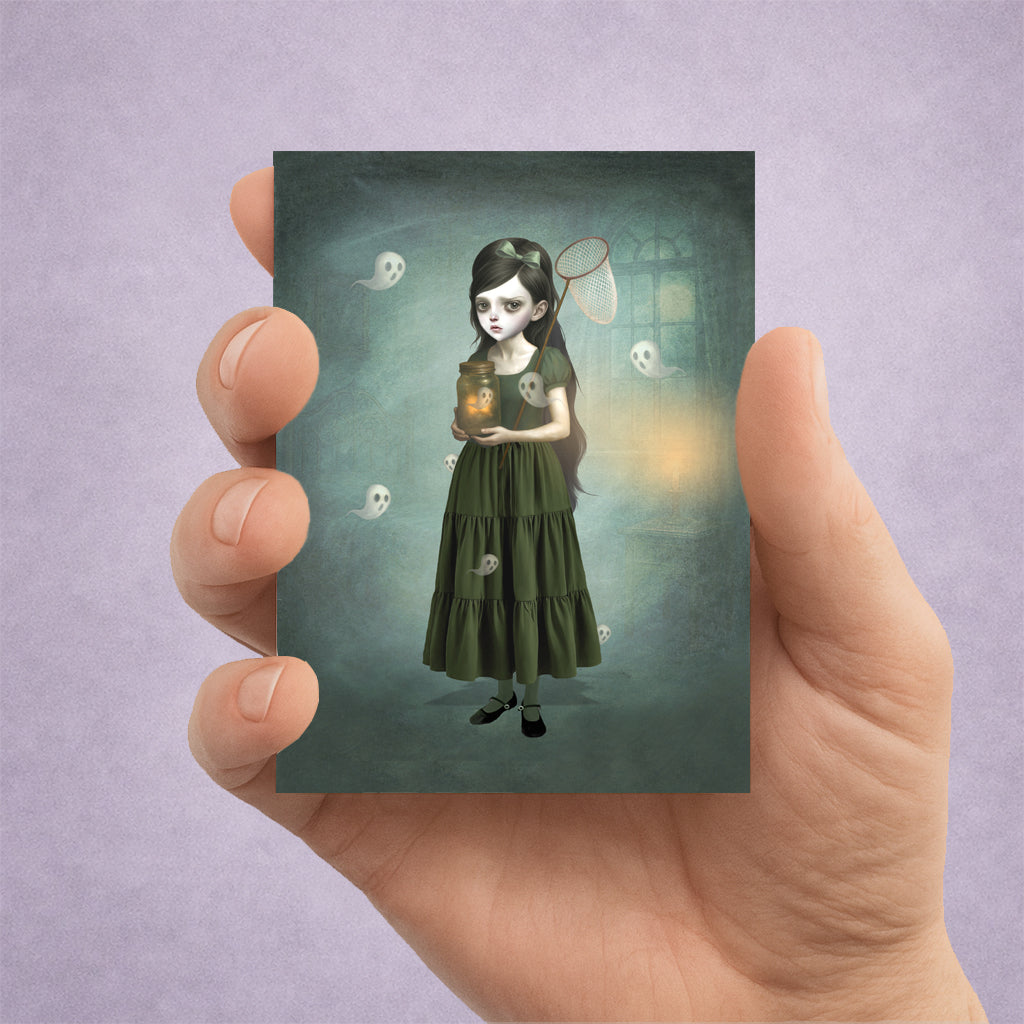 A spooky cute ACEO art card Features a girl catching ghosts—perfect for miniature whimsical gothic decor. Held in hand to display size.