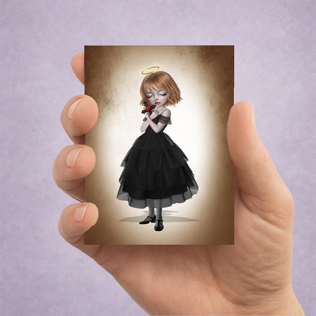Hand holding an ACEO art card featuring a gothic girl with a halo in a black dress holding a crucifix with a red rose.
