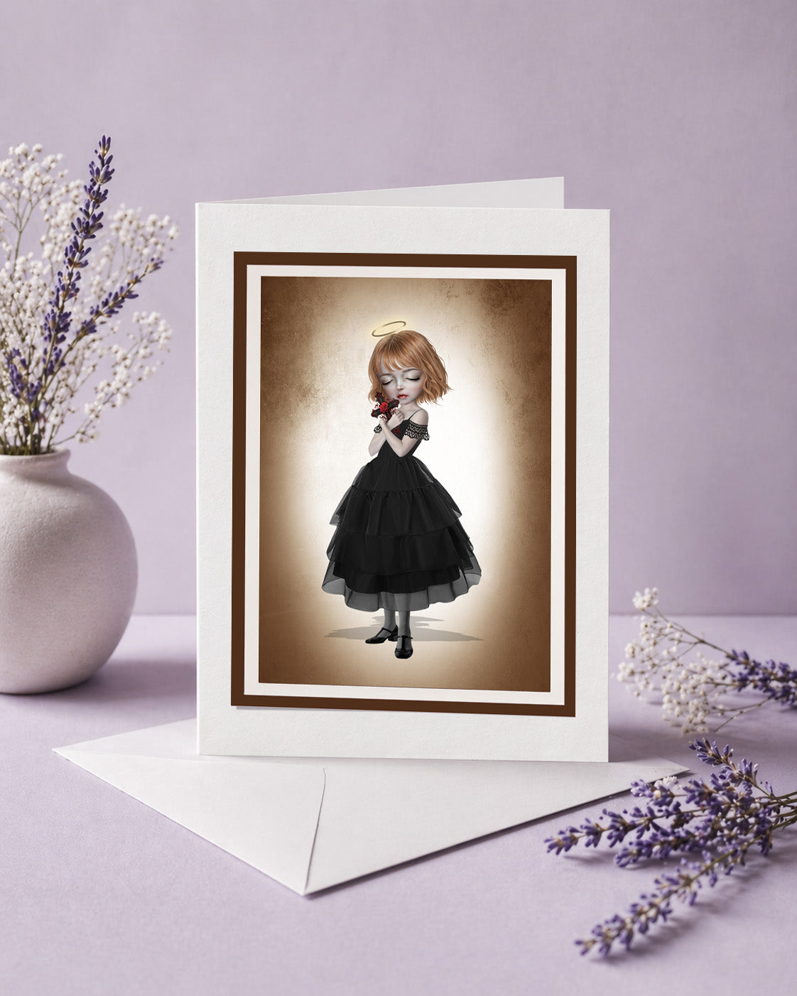 Blank gothic art greeting card featuring an angelic girl holding a crucifix, displayed with an envelope and lavender sprigs.