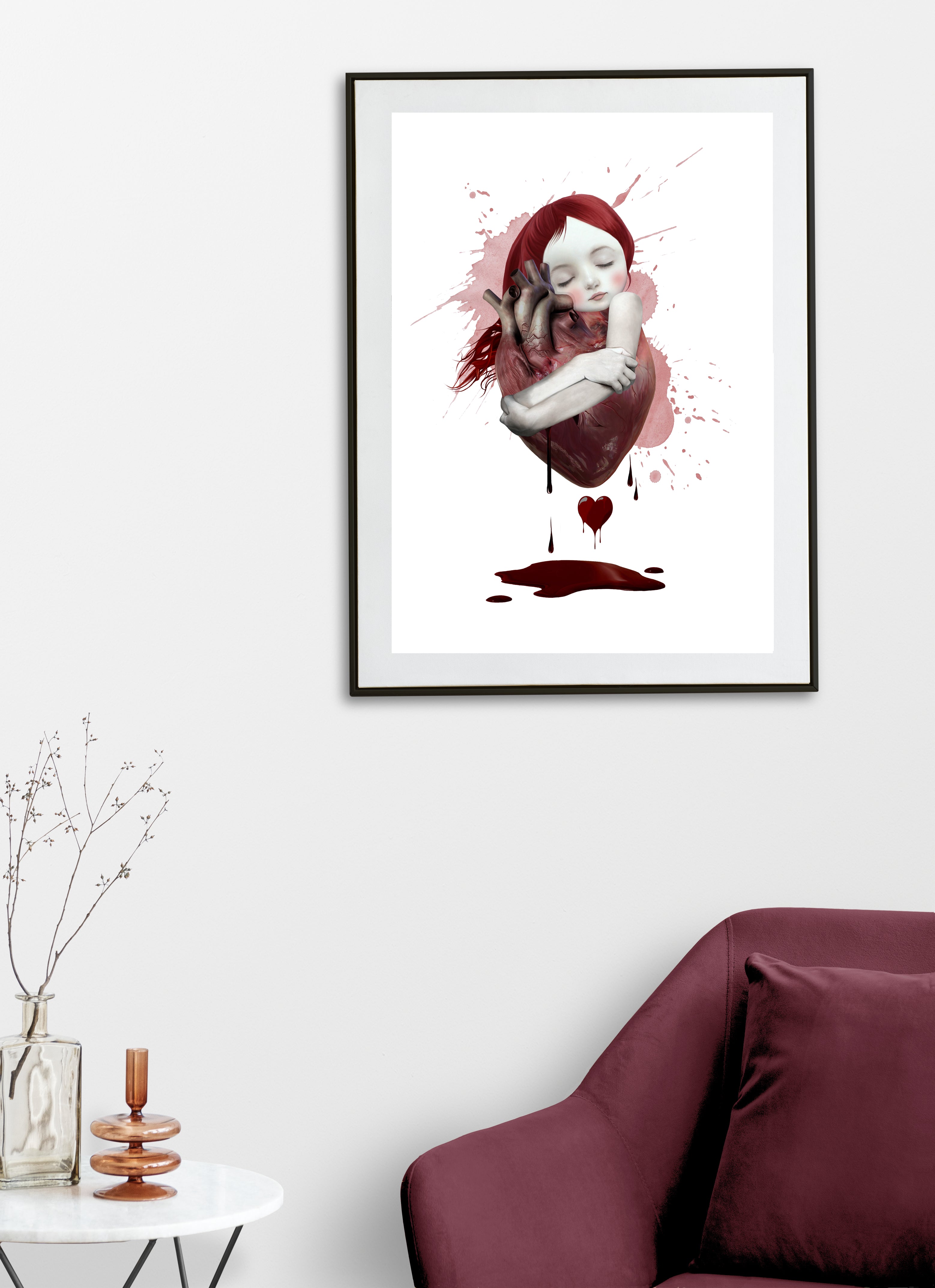 Framed artwork of a woman embracing an oversized human heart with red hair on a white background.