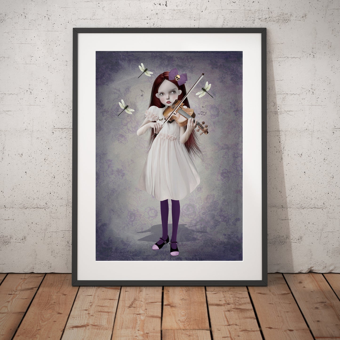 Girl and dragonflies art print in a black frame, standing against a white wall.