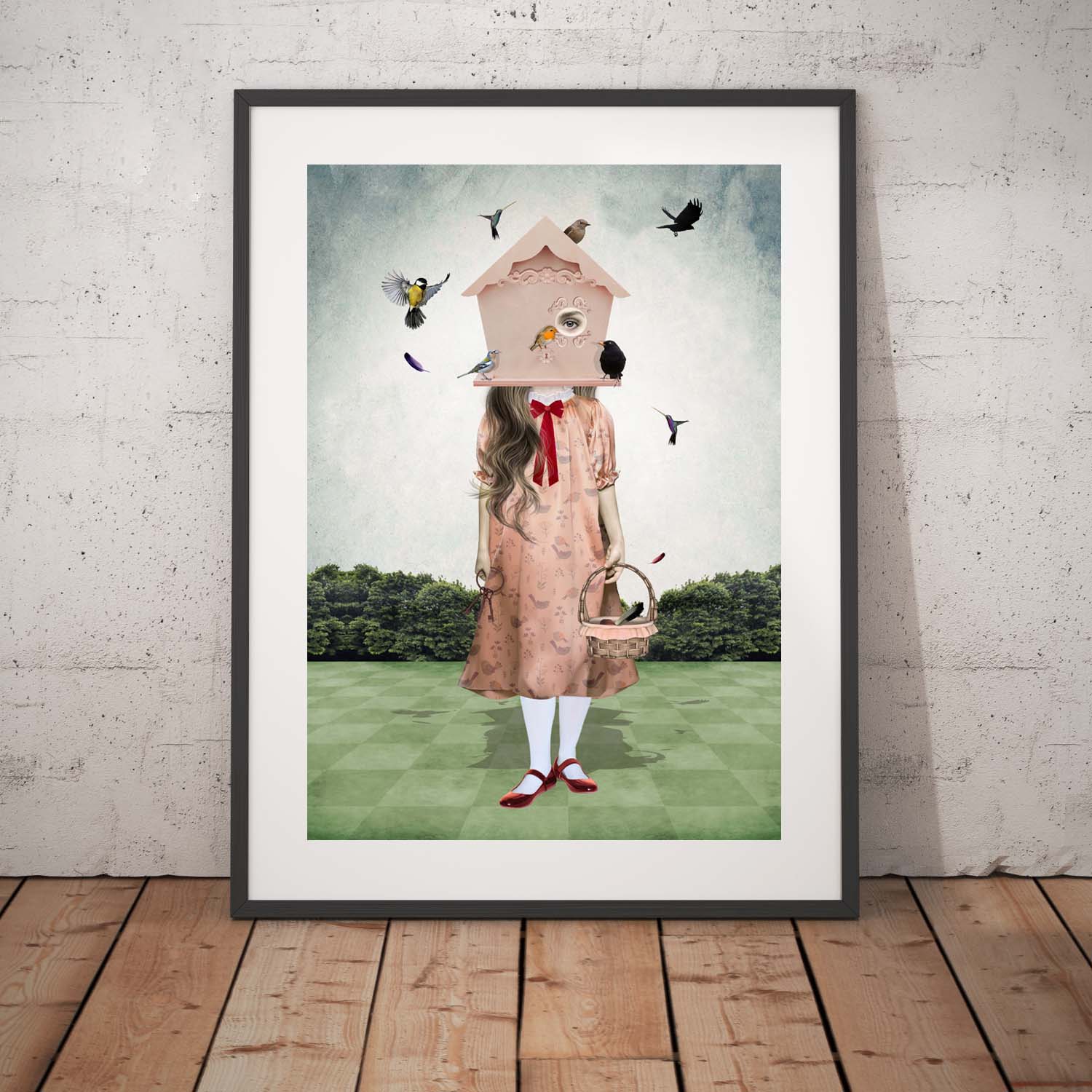 Girl and garden birds art print in a black frame, standing against a white wall.