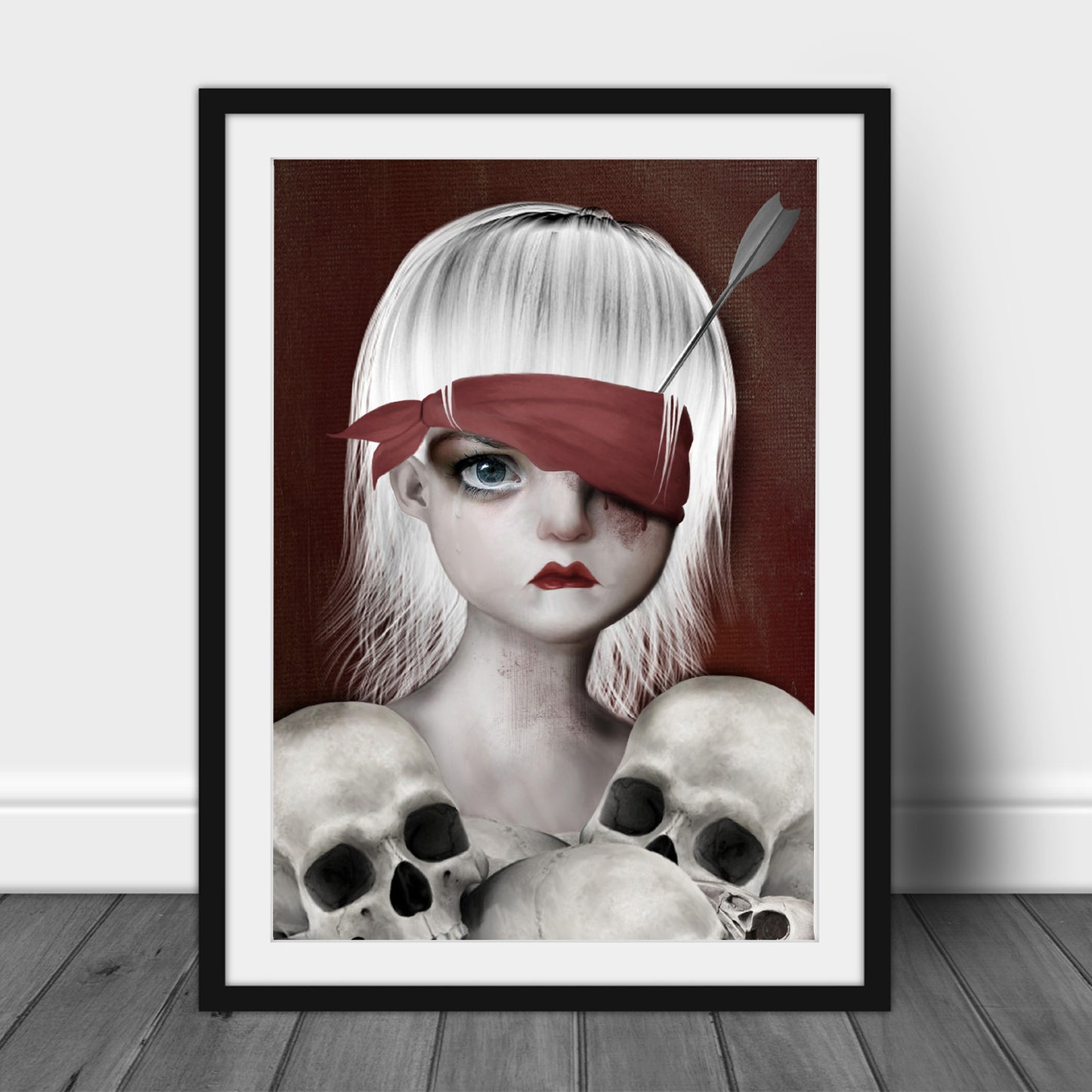 Macabre Art Print in frame. Featuring a girl with an arrow in her eye surrounded by human skulls.