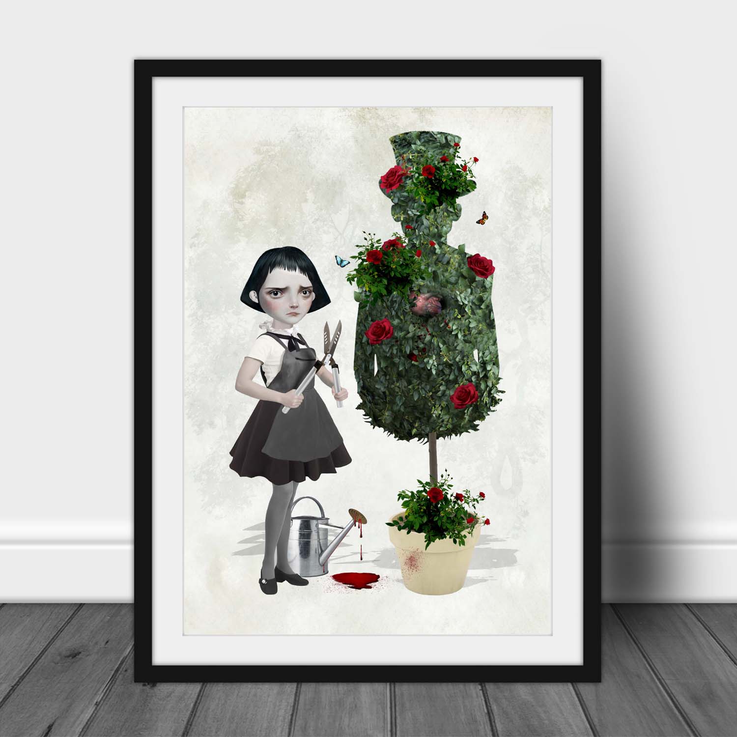 Art print of a goth girl and topiary, in a frame leaned against a wall.