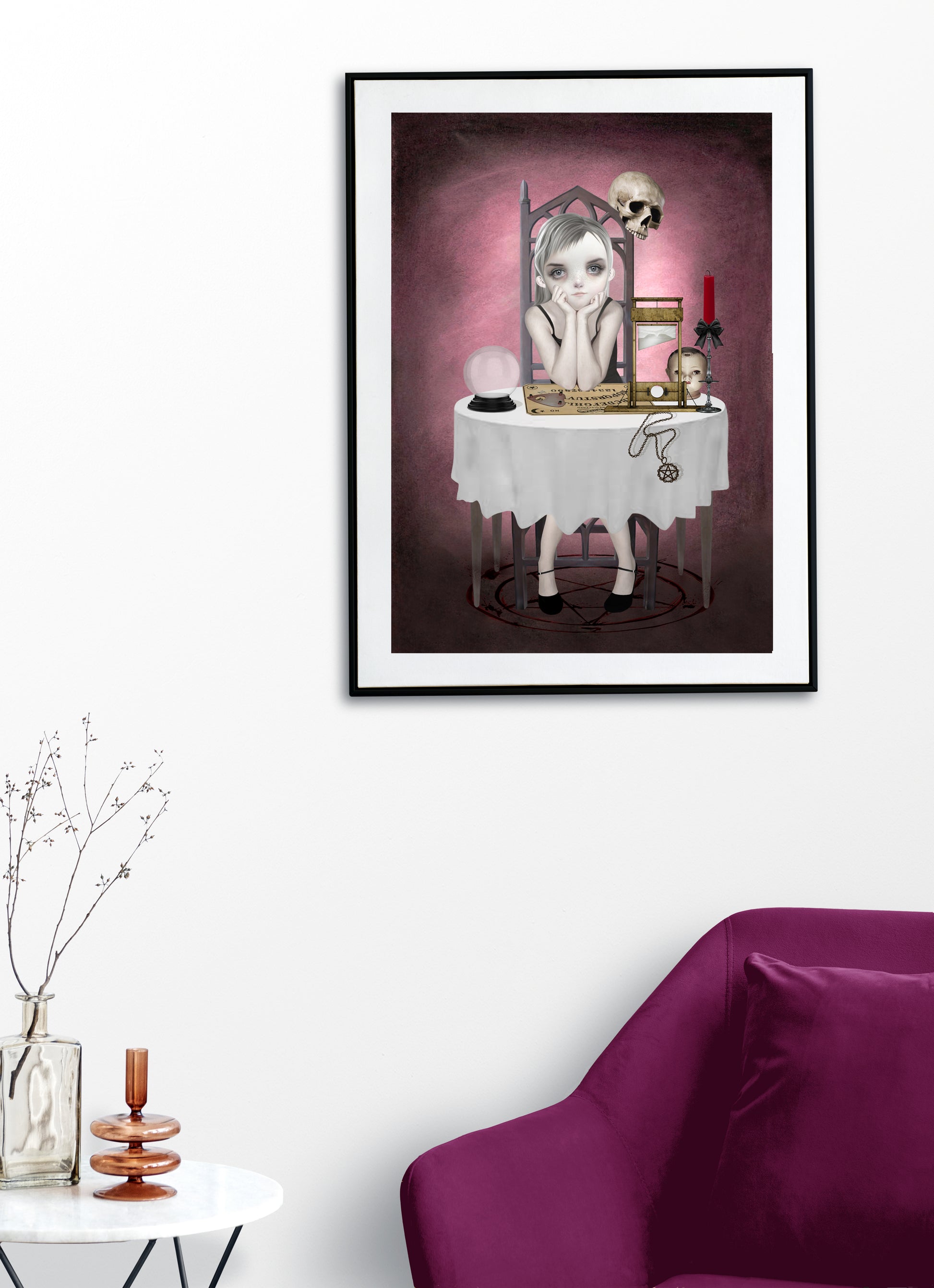 A goth girl art print with a Ouija board, framed and hanging on a living room wall. Perfect for adding a creepy cute touch to gothic or alternative home decor.