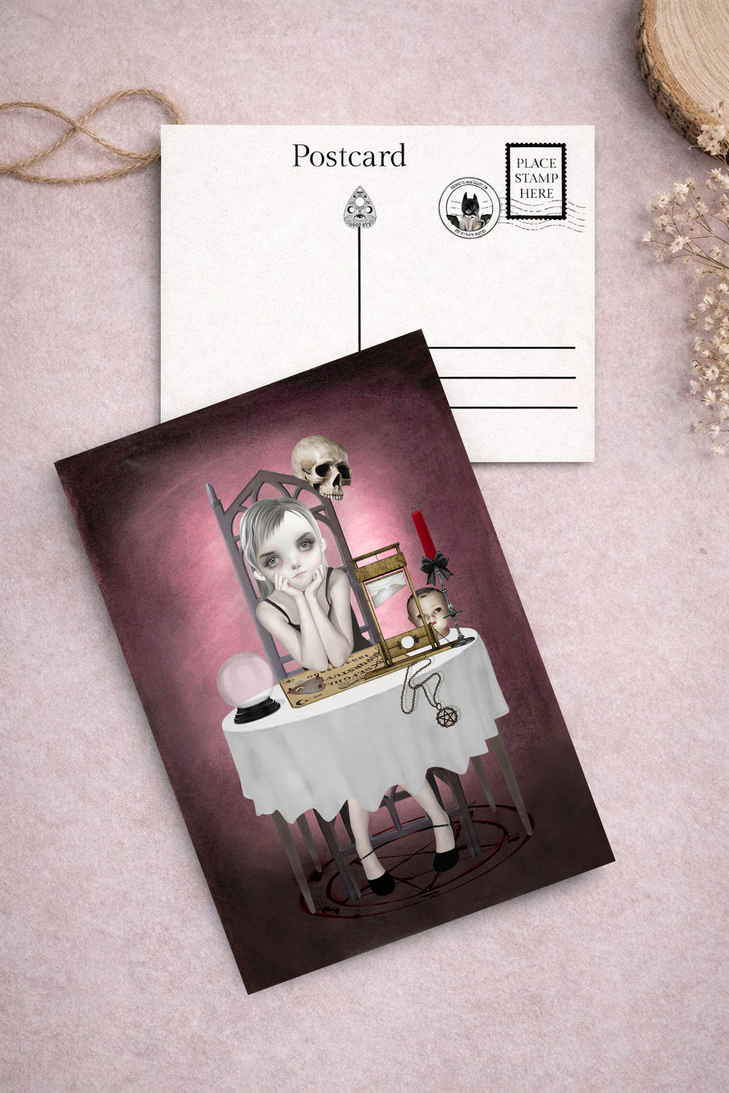 Gothic-themed postcard goth girl with a ouija board and candles on a table.