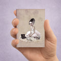 Hand holding an ACEO card with a artistic design of a gothic ballerina with a music box and skull.
