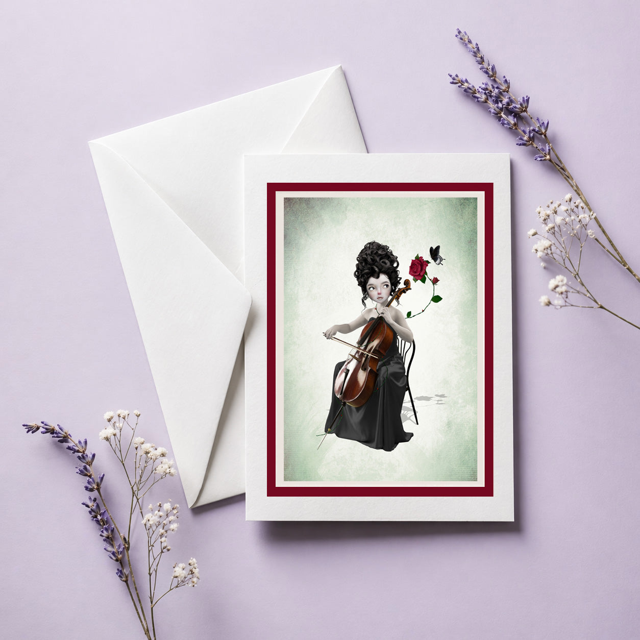 Greeting card with a woman playing a cello beside a rose and black butterfly, accompanied by a white envelope on a light purple background.