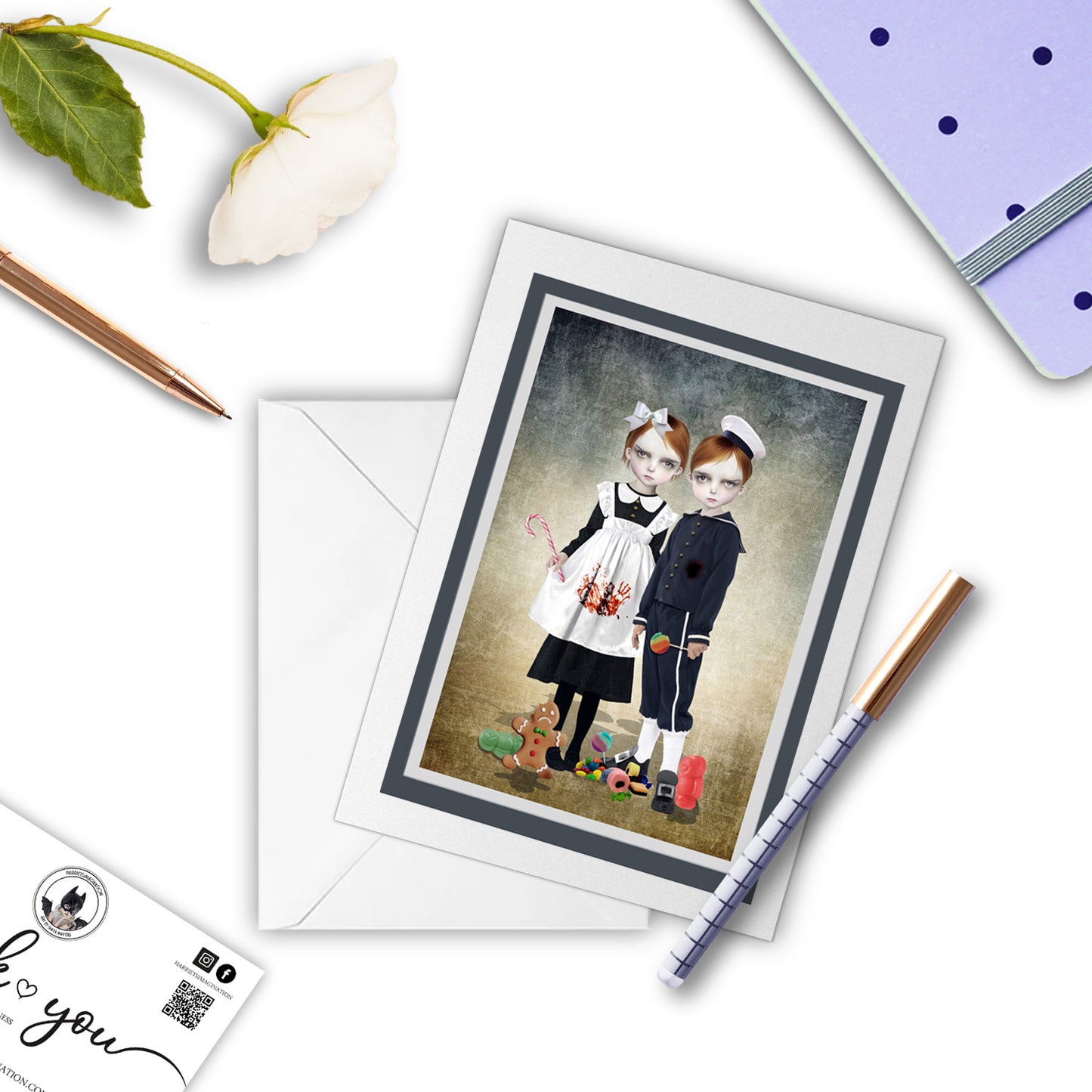 Gothic Fairytale Hansel & Gretel Art Greeting Card, with a pen and other stationary items arranged around it.