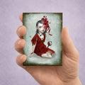 ACEO art print held in hand. Dark fantasy surrealism miniature print featuring a gothic girl in a red dress with cracked skin and bugs.
