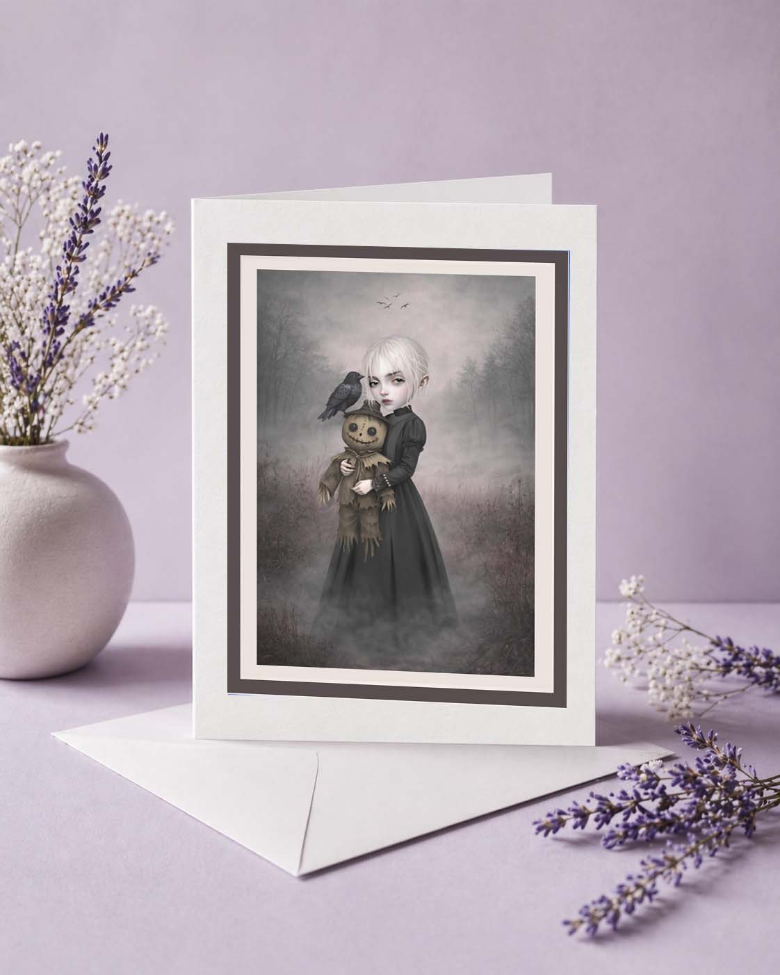 This eerie greeting card features a pale, platinum-haired girl in a dark Victorian-style dress cradling a stitched, creepy-cute scarecrow doll.