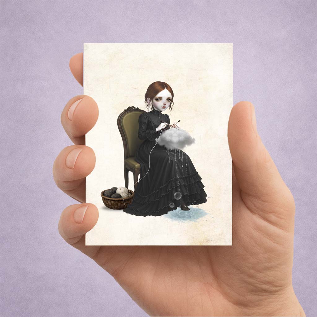 A miniature gothic ACEO art card featuring a surreal illustration of a girl knitting a raincloud while sitting on a vintage chair, held upright in a person's hand against a textured purple background.