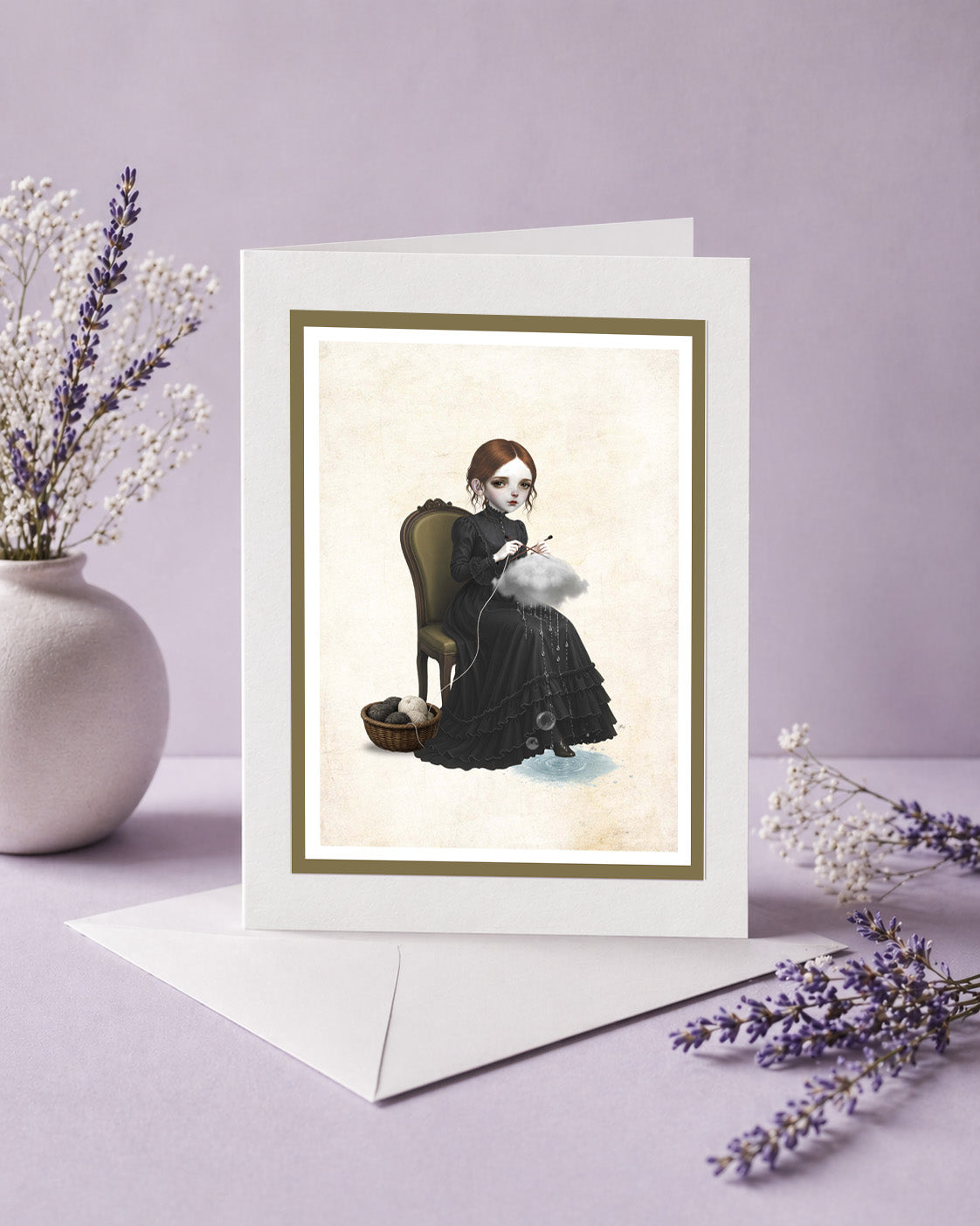 An alternative art greeting card featuring a dark whimsy pop surrealism illustration of a girl knitting a raincloud while sitting on a vintage chair, standing upright on its white envelope next to a ceramic vase with dried lavender on a purple background.