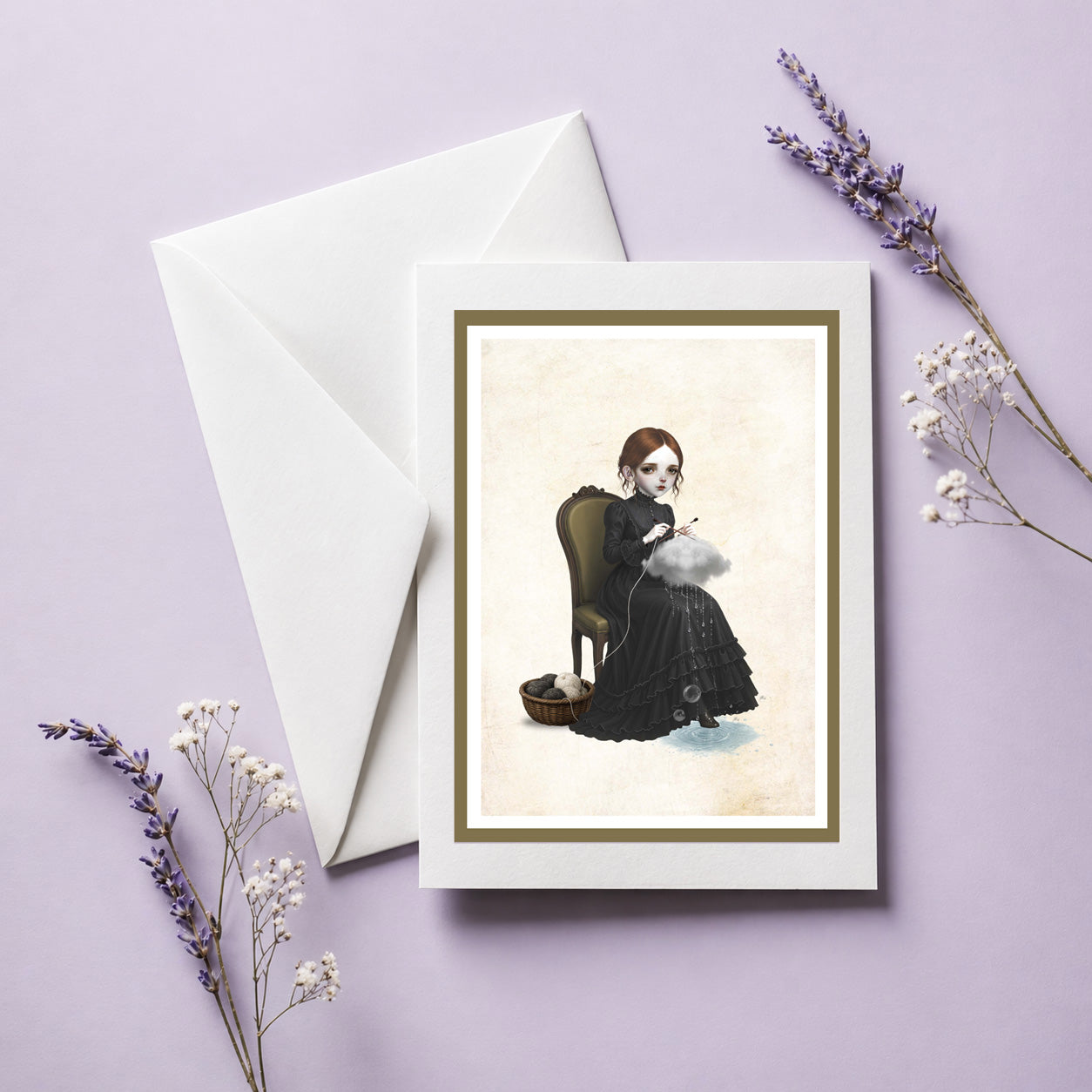 An alternative art greeting card with an envelope featuring a dark whimsy pop surrealism illustration of a girl knitting a raincloud while sitting on a vintage chair