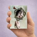Dark surrealism ACEO art card held by hand featuring a gothic mirror, stitched portrait reflection and butterfly.