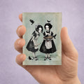 Miniature 2.5x3.5 ACEO art card displayed in hand, featuring twin gothic girls with blackbirds and a pie in a dark cottagecore style.