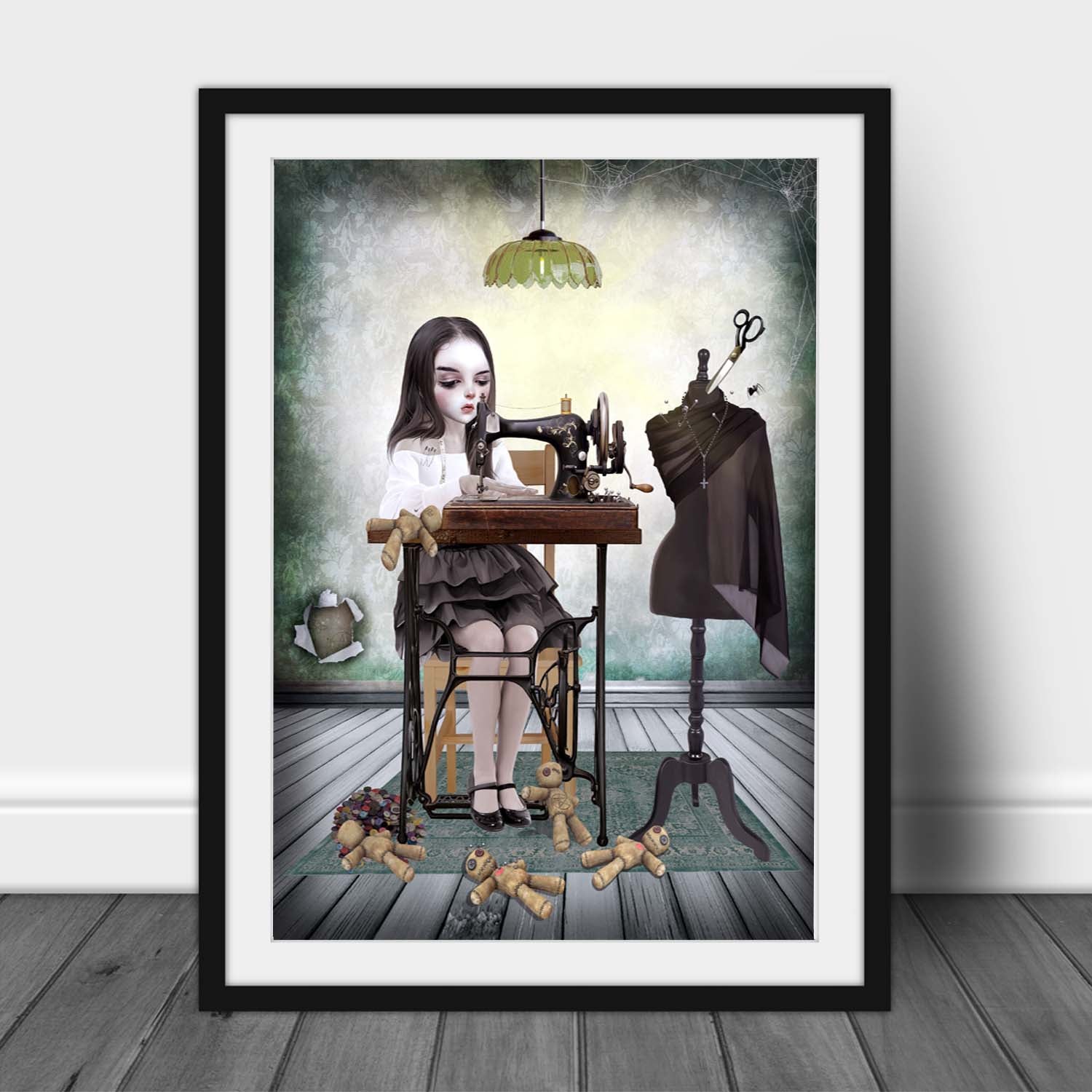Framed artwork of a girl at a sewing machine creating voodoo dolls.