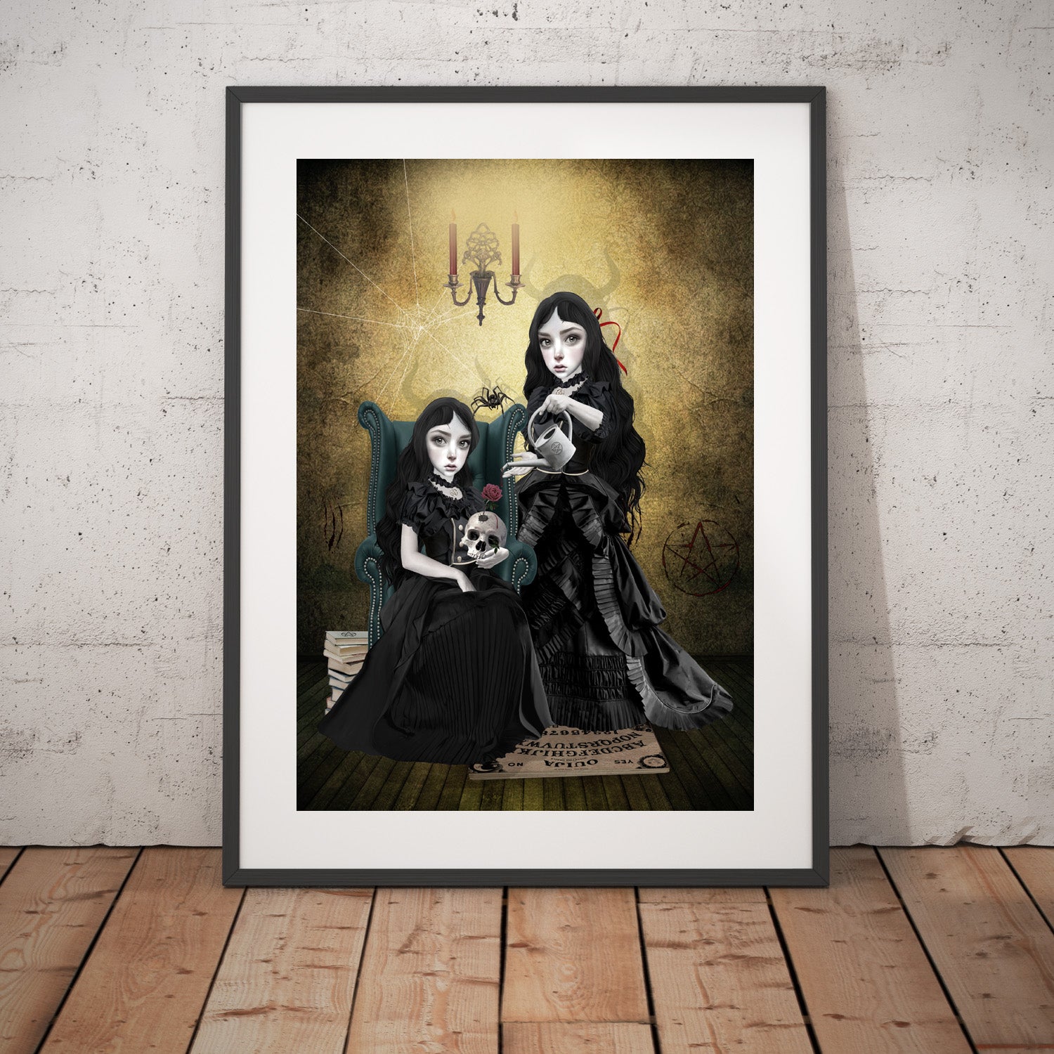 Gothic sisters at witching hour art print in a black frame, standing against a white wall.