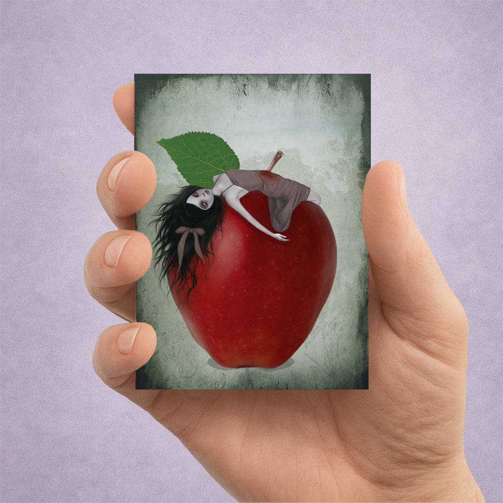 Hand holding an ACEO card with an illustration of Snow White impaled on an oversized red apple stalk.