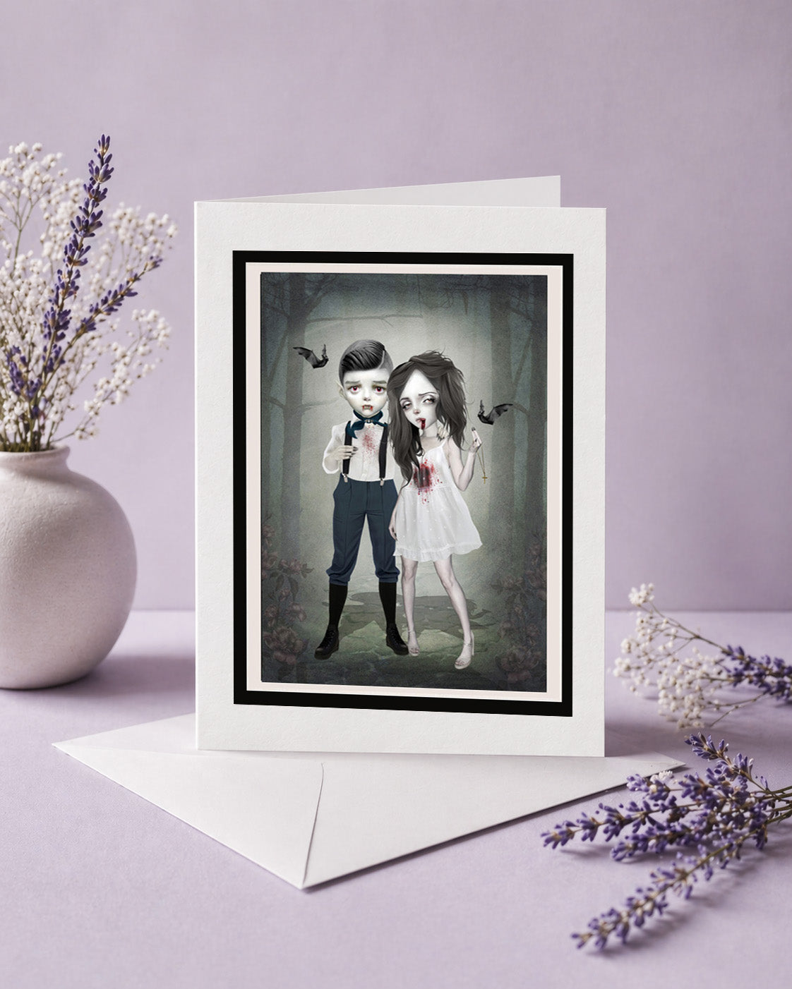 Greeting card with a framed illustration of gothic vampire couple forever young on a purple background with flowers.